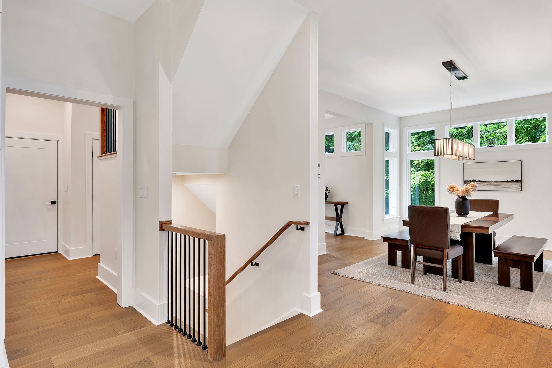 A dining room with a table and chairs and a staircase in a house.