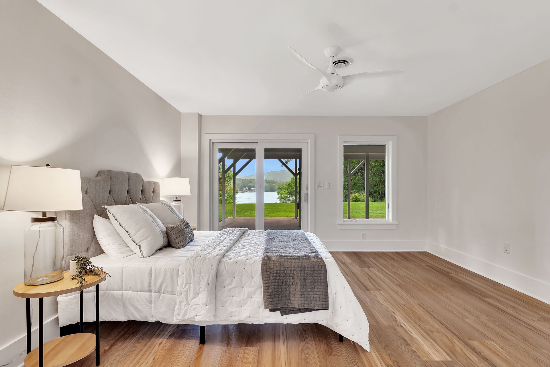 A bedroom with a bed , lamps , and a ceiling fan.
