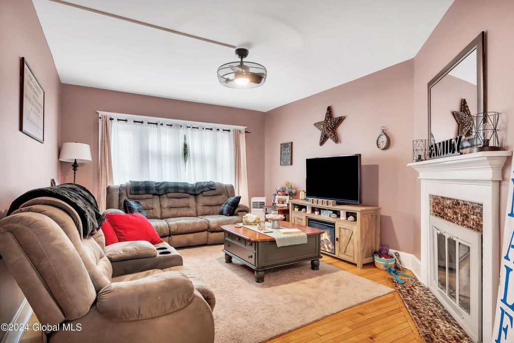 A living room with a couch , chair , coffee table , television and fireplace.