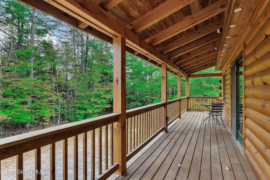A large wooden deck with a covered roof and trees in the background