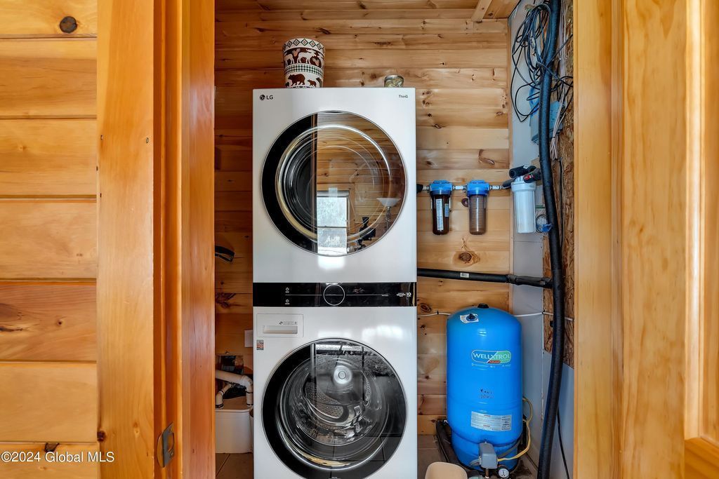 A washer and dryer are stacked on top of each other in a wooden room.