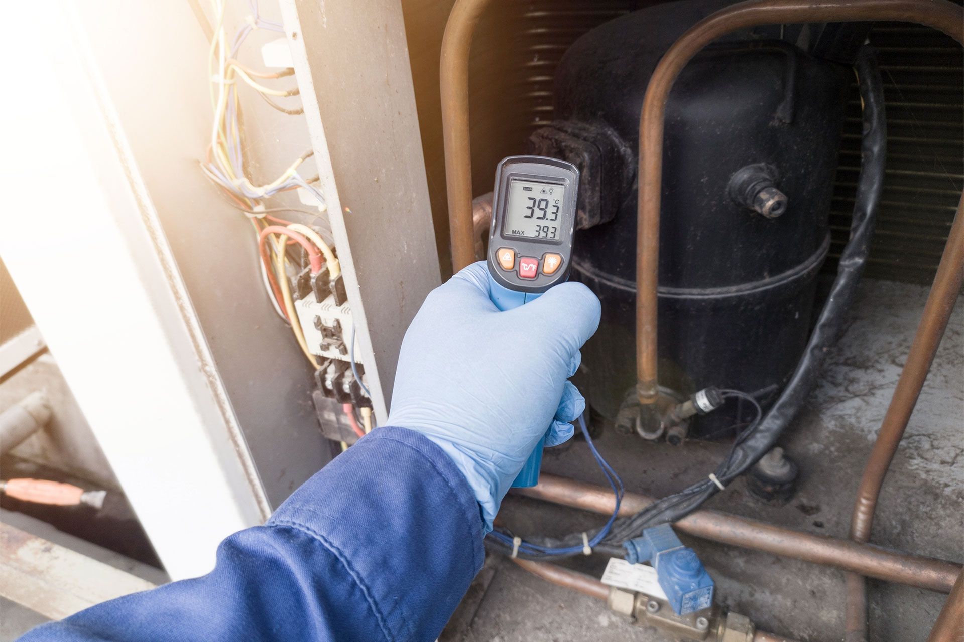 A person is holding a thermometer in their hand in front of a refrigerator.