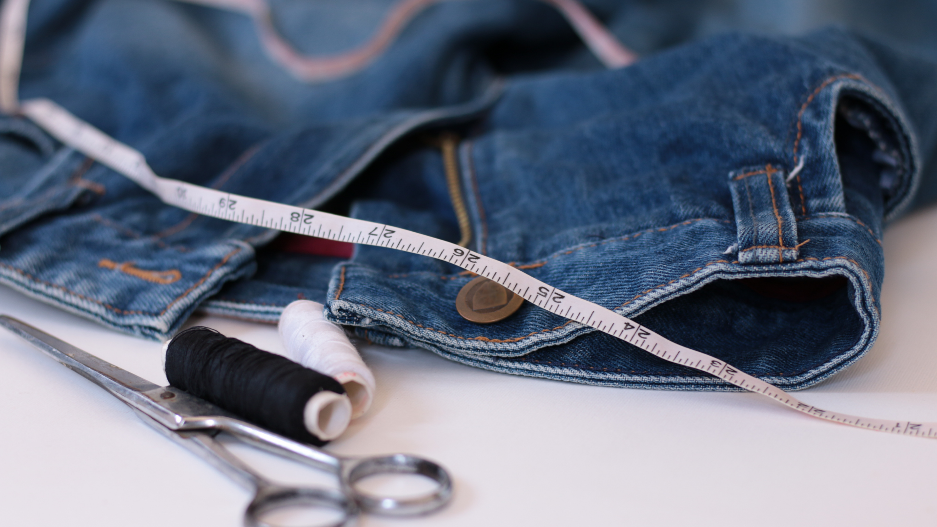 A pair of jeans with a measuring tape and scissors on it