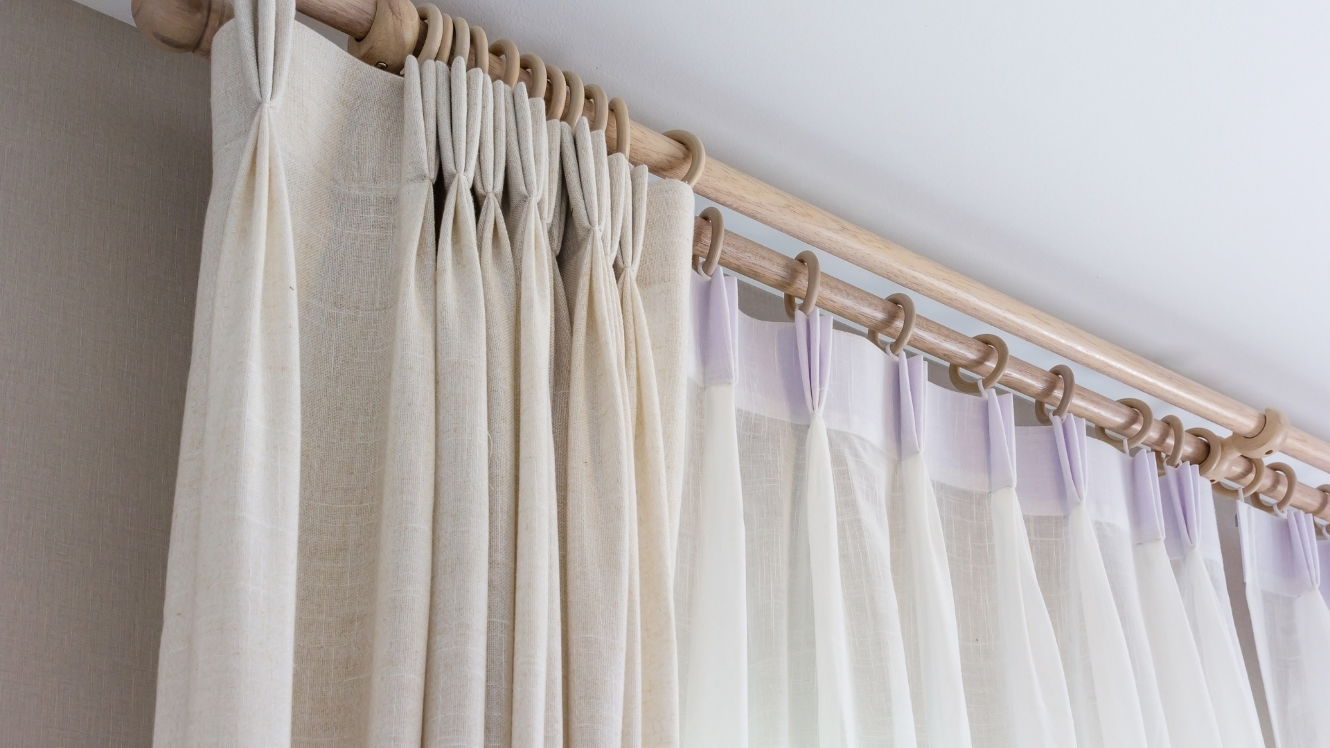 A close up of a pair of curtains hanging from a wooden pole.