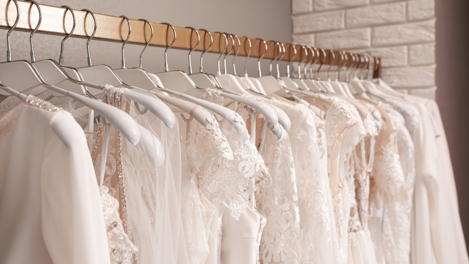 A row of white dresses hanging on a rack in a store.