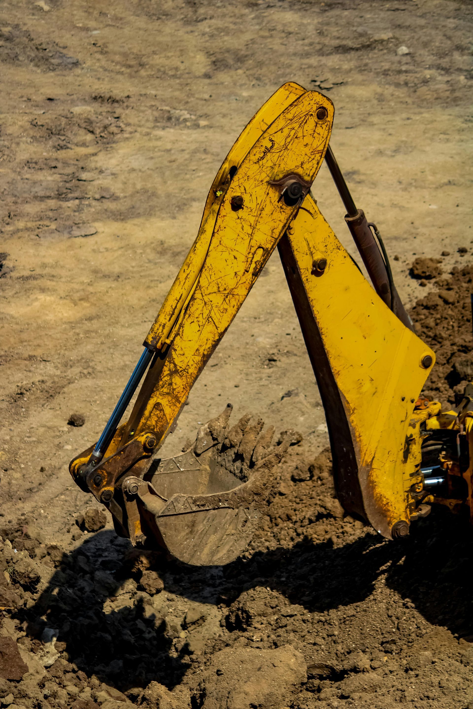 A yellow excavator is digging a hole in the dirt