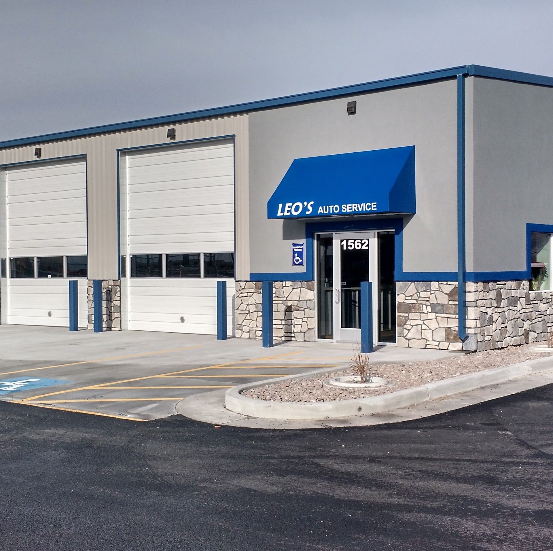Exterior of a blue-and-gray warehouse with loading bays and a blue awning entrance | Leo's Auto Service