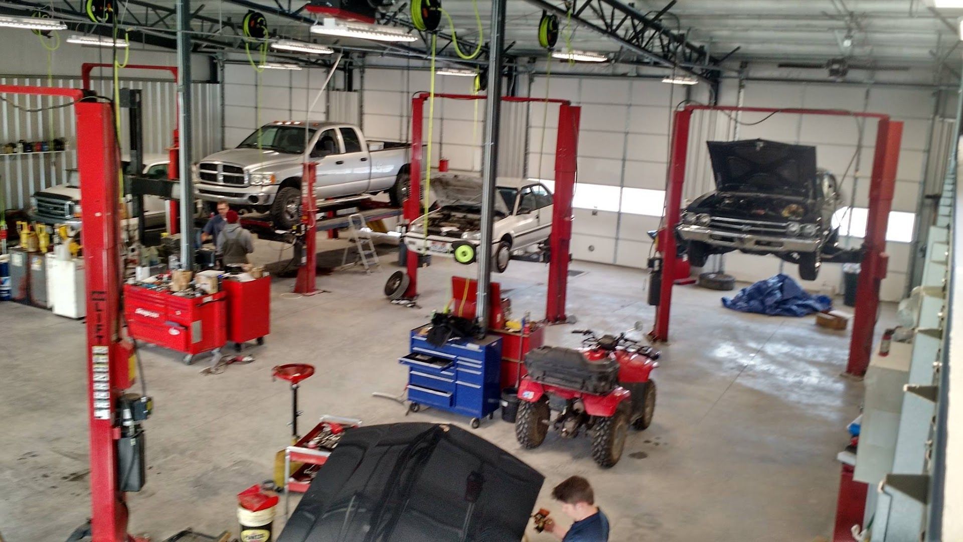 Auto repair shop with cars on lifts, tool carts, and a work truck in the background | Leo's Auto Service