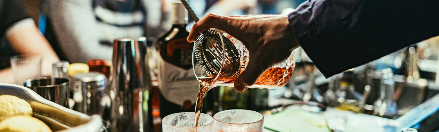 A bartender is pouring a drink into a glass.