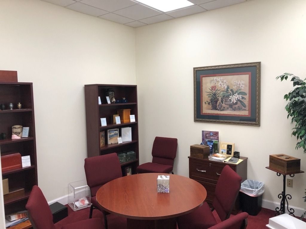 Small room with round table, chairs, bookshelves, and floral artwork.