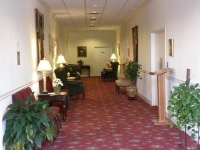 Long hallway with red carpet, seating areas, and plants.