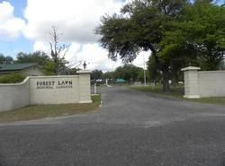 Entrance to Forest Lawn Memorial Gardens with sign and driveway.