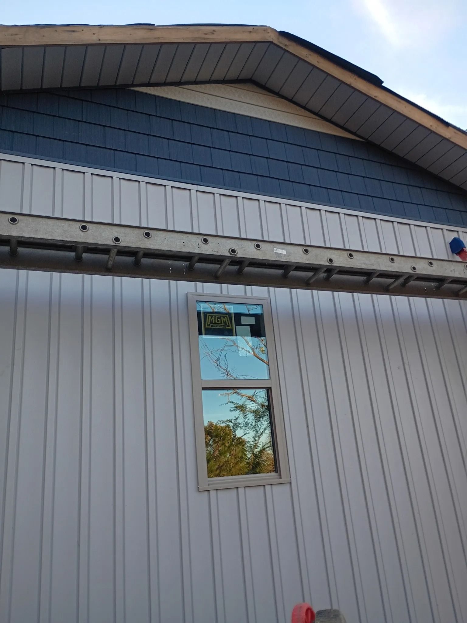 Exterior of a white house with blue upper siding and a small window under the eaves