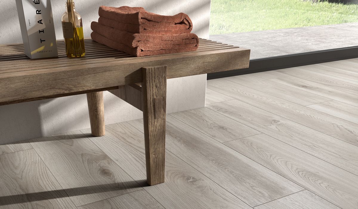 Rustic tréborð með brotnum brúnum dúk, flösku og ljósu viðargólfi í björtu herbergi