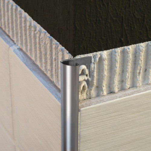 Nærmynd af silfurlituðum málmhornlist á beige bylgjupappaplötum.