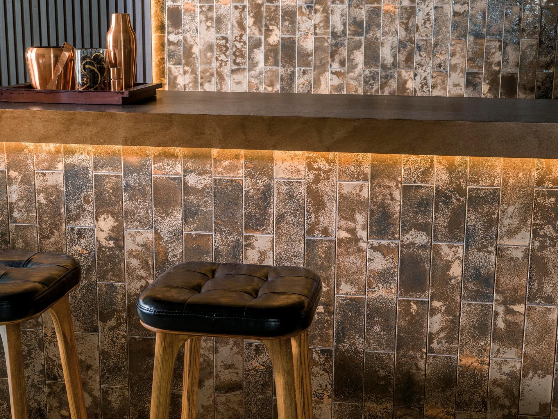 Bar með tveimur hægðum og flísalögðum vegg.