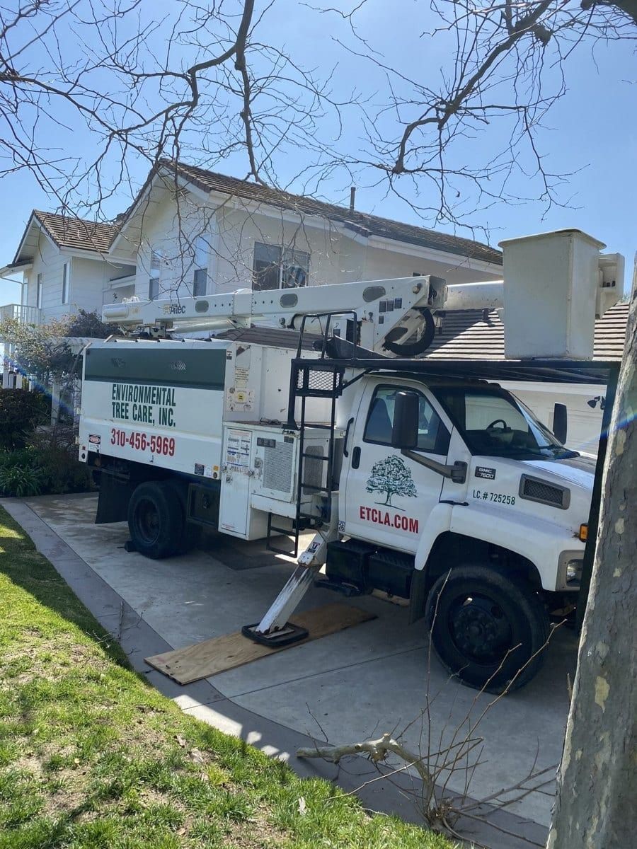 White utility truck with boom lift parked in front of a house on a residential street