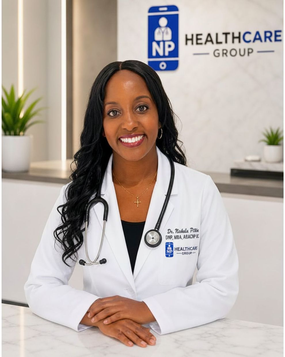 Healthcare professional in a white coat smiling at a clinic reception desk, with a healthcare group sign behind her.