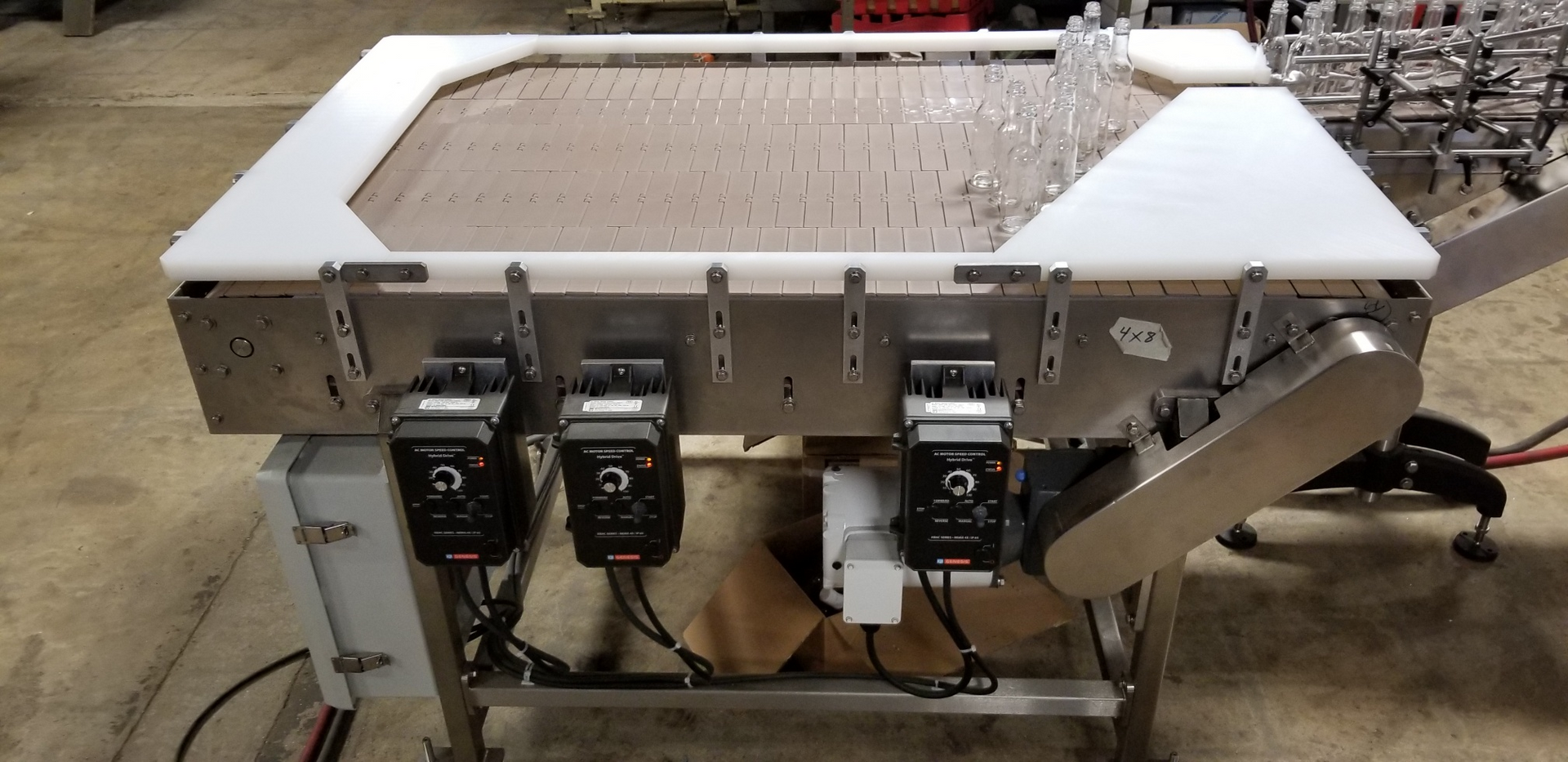 An industrial accumulation table with a brown conveyor belt.