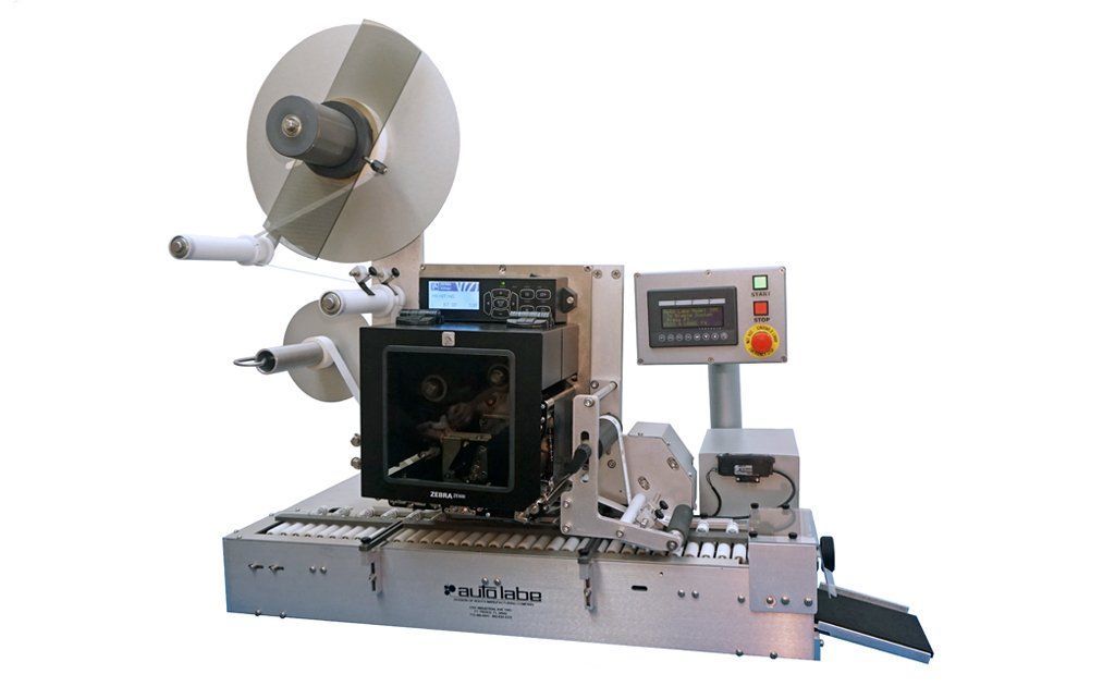 An industrial labeling machine with a large roll of labels.