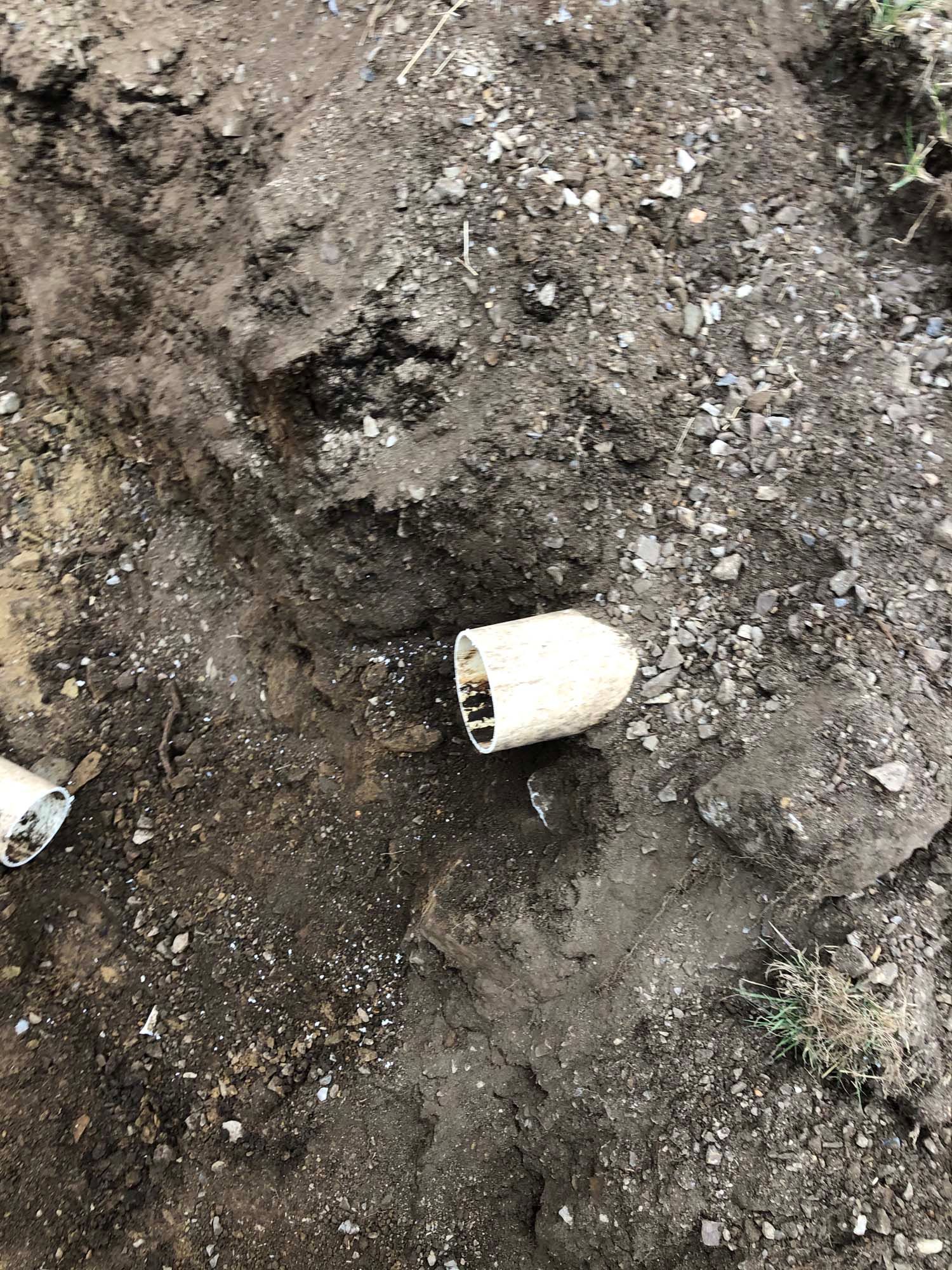 A white disposable cup лежing on muddy ground with scattered gravel and debris.