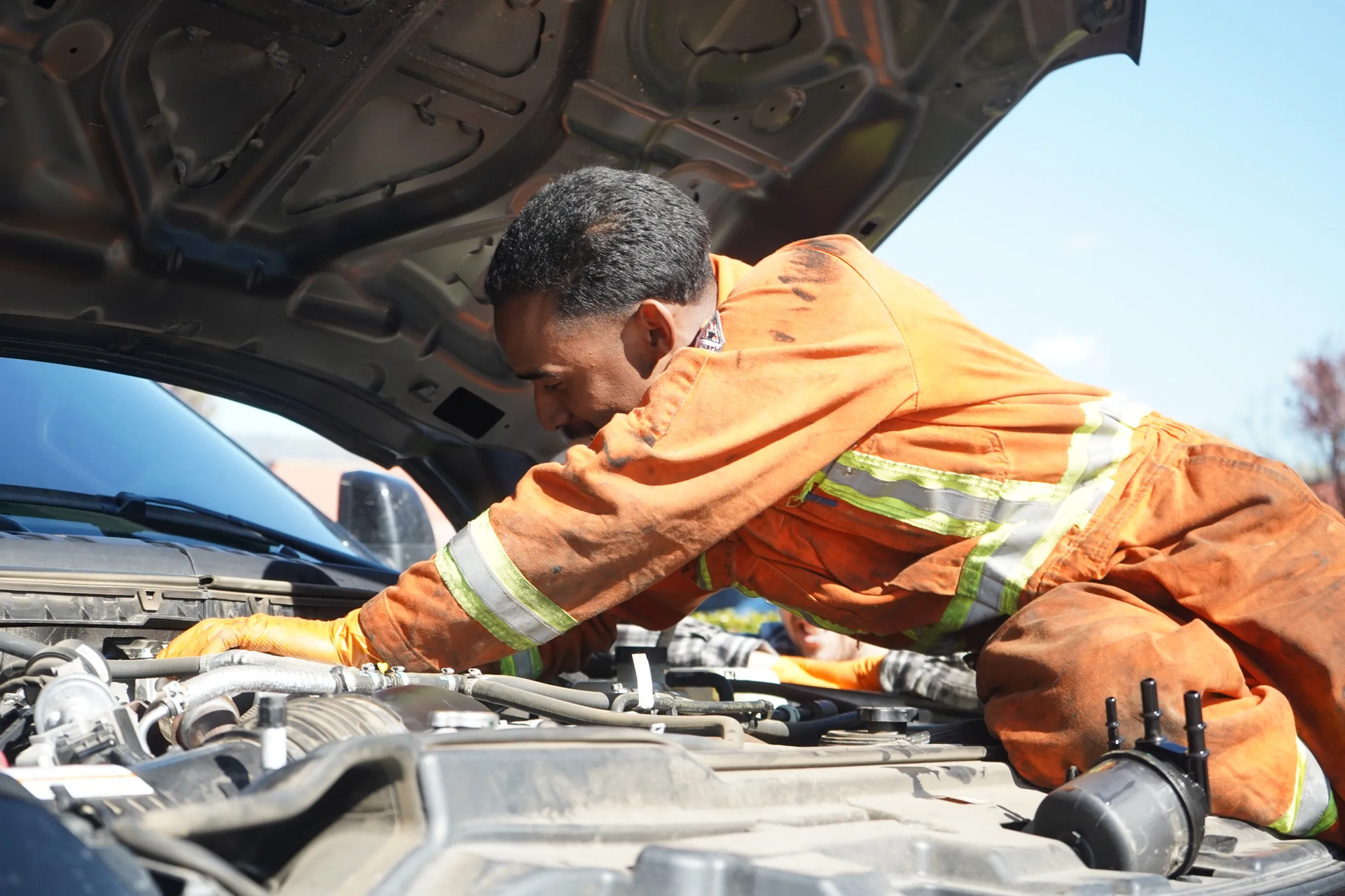 A man is working under the hood of a car.