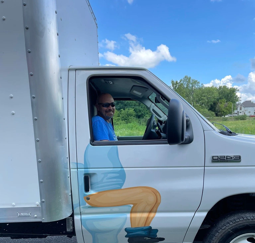 White box truck with a driver smiling out the window on a sunny day.