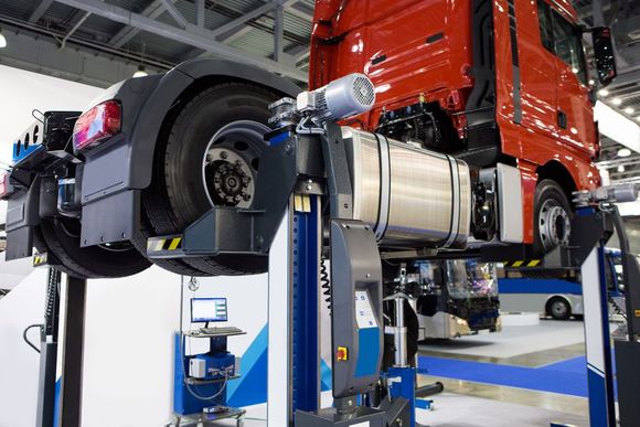 A red truck is sitting on top of a lift in a garage.