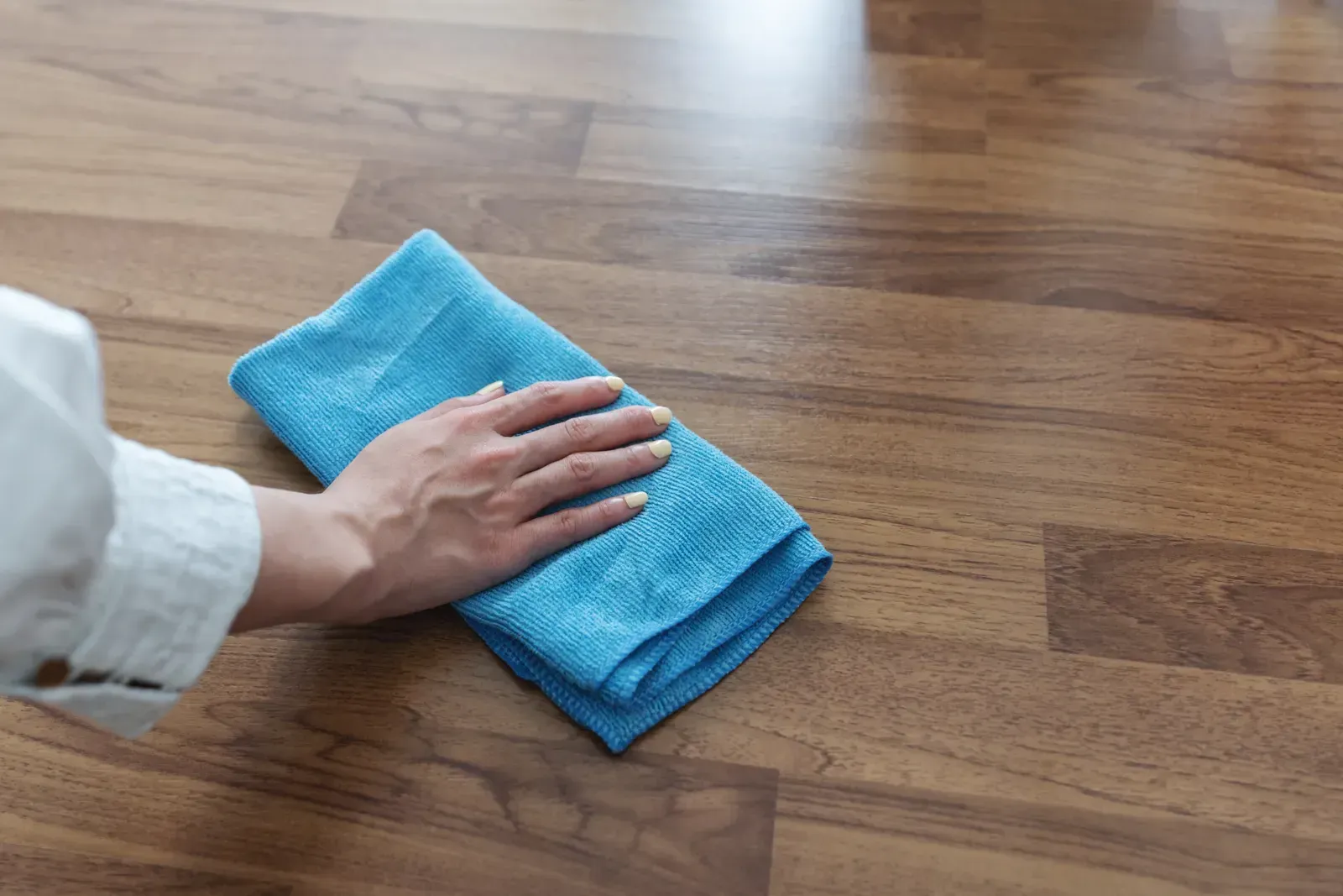 A person is cleaning a wooden floor with a blue towel. A person is cleaning a wooden floor with a blue towel.