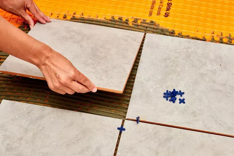 Someone replacing a damaged tile with grout and cement. Someone replacing a damaged tile with grout and cement.