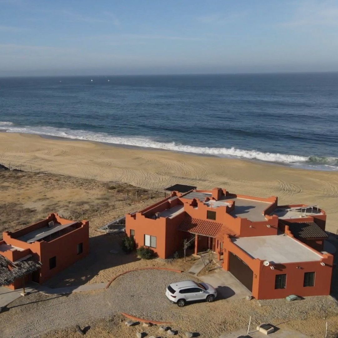 an aerial view of a house on the beach with a car parked in front of it