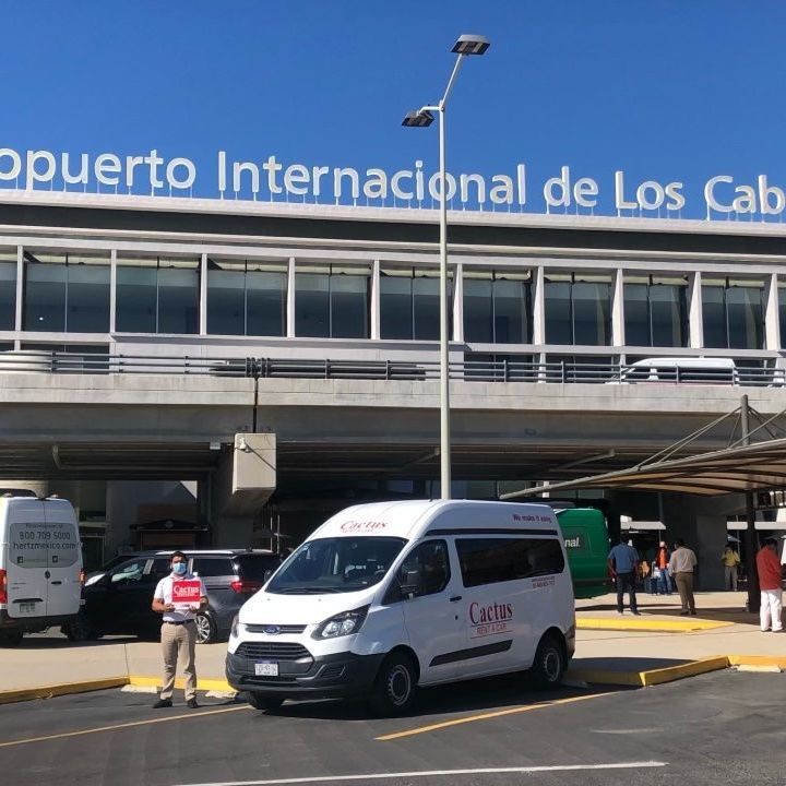 a white van is parked in front of the aeropuerto internacional de los cabos