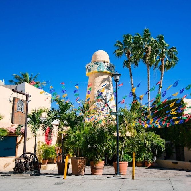 a lighthouse is surrounded by palm trees and flags