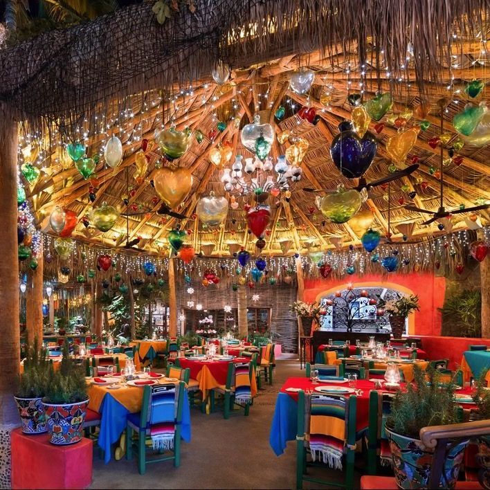 a restaurant with tables and chairs under a thatched roof