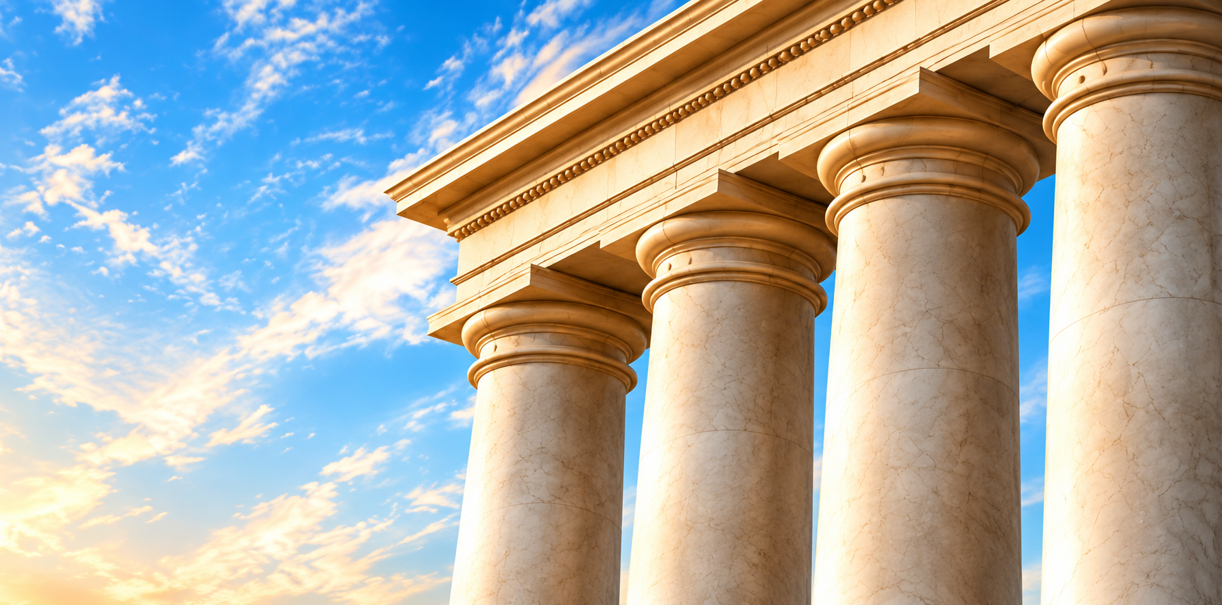 Sunlit classical stone columns against a blue sky with clouds