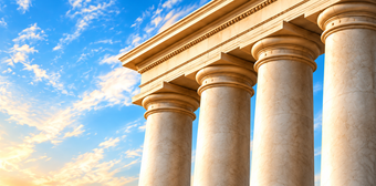 Sunlit classical stone columns against a blue sky with clouds