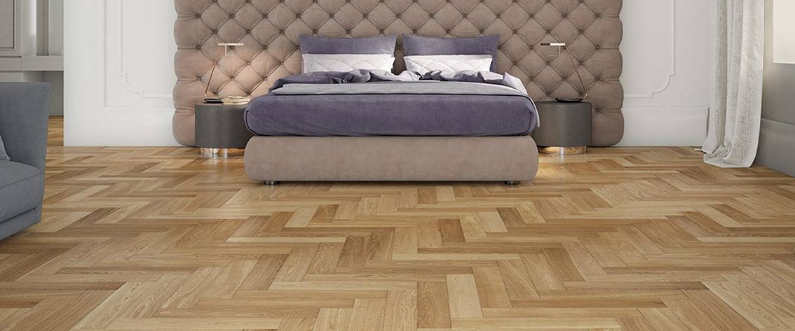 Una camera da letto dotata di un letto con testiera imbottita e pavimento in legno.