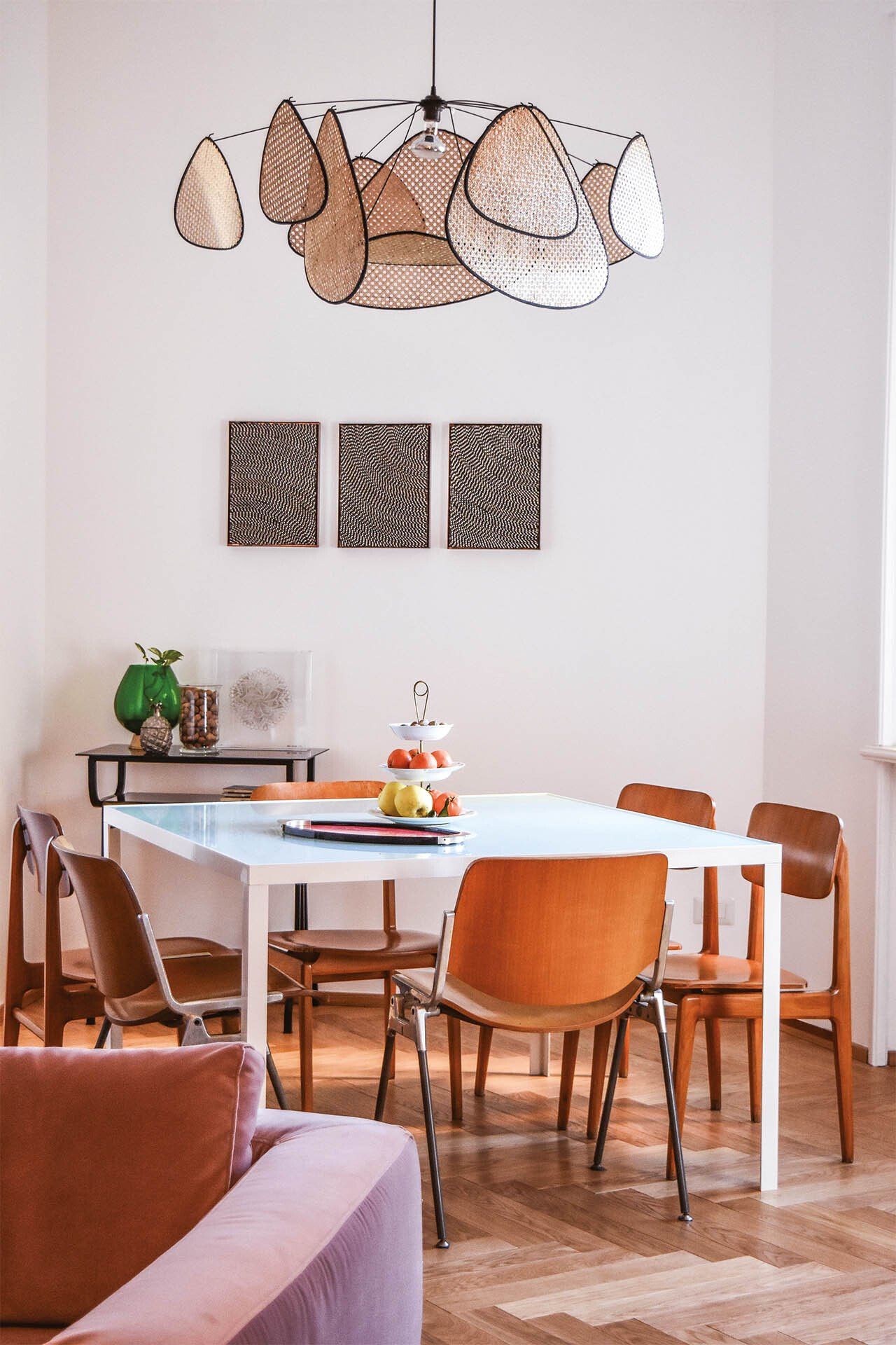 Sala da pranzo con tavolo, sedie e lampadario unico. Opere d'arte alle pareti.