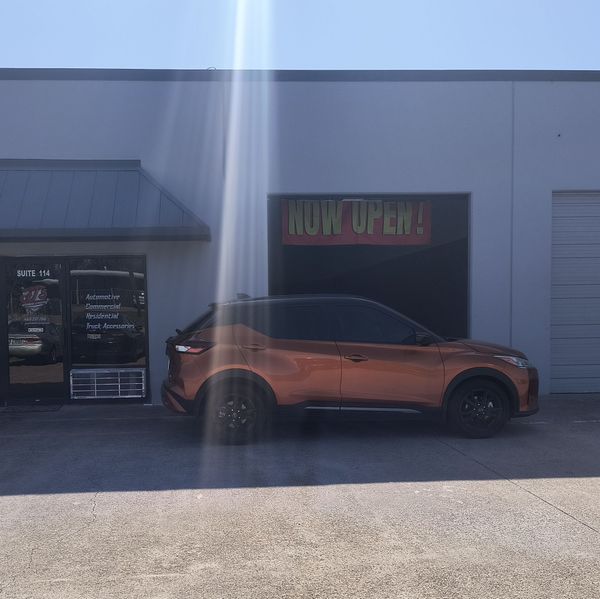 Orange SUV parked outside a building with a neon “NO U TURN” sign in the window