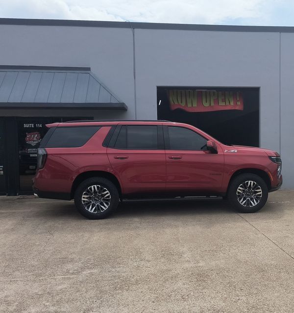 Red SUV parked outside a gray building with a service bay.