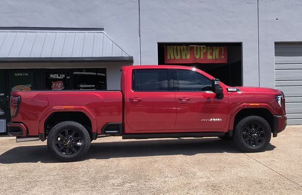Red pickup truck parked outside a shop with a gray facade
