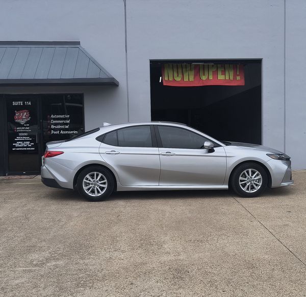Silver sedan parked outside a building with black windows and red-yellow signage.