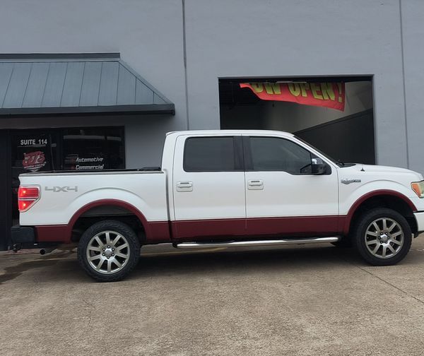 White Ford pickup truck with red lower trim parked outside a building