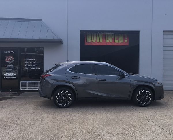 Dark gray sedan parked in front of a building with a neon “Hunt Open” sign