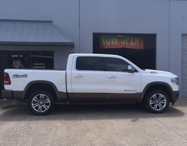 White pickup truck parked outside a building with a neon “NOW OPEN” sign
