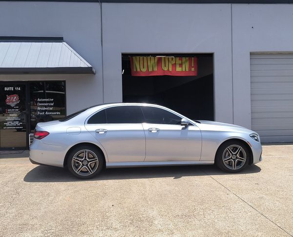 Silver sedan parked outside a storefront with a neon “NOW OPEN” sign.
