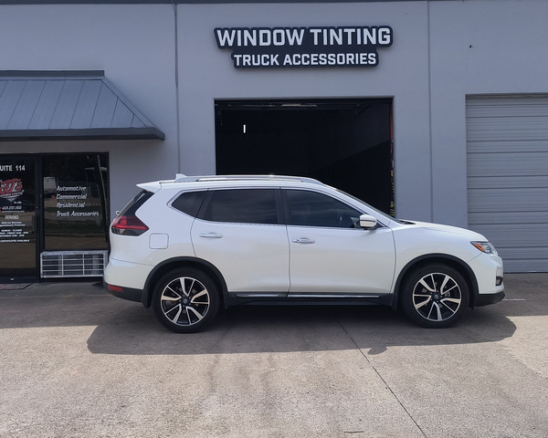 White SUV parked outside a window tinting and truck accessories shop.