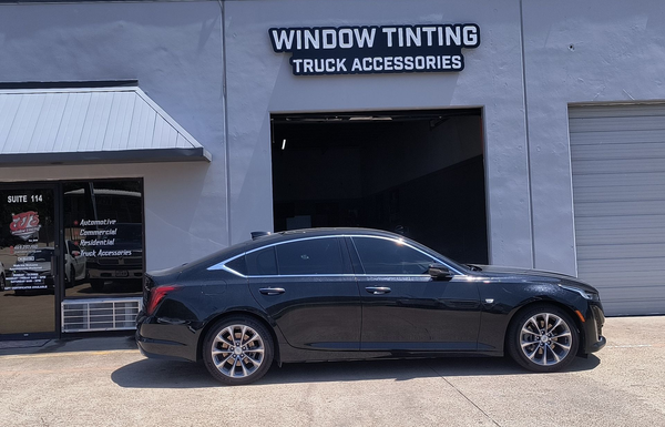 Black luxury coupe parked outside a window tinting and truck accessories shop