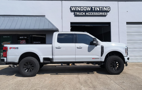White lifted pickup truck parked outside a window tinting truck accessories shop