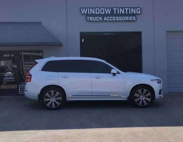 White SUV parked outside a window tinting truck accessories shop